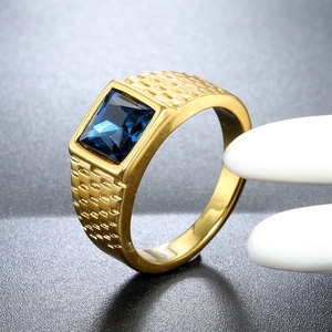 Macro shot of gold-plated men's ring with square blue gemstone and engraved texture