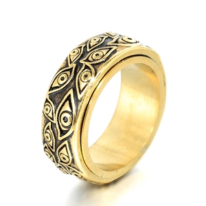 Gold spinner ring with evil eye relief motifs and rotating polished stainless steel band