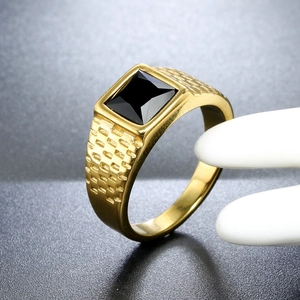 Macro detail of men's stainless steel gold ring with square black stone and embossed sides