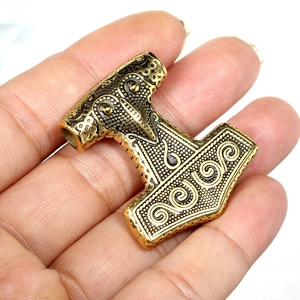 Primer plano detallado del colgante Mjölnir bañado en oro con grabados nórdicos