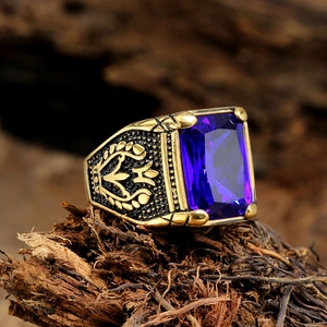 Macro detail of vintage gold ring with rectangle blue gemstone and embossed heraldic carvings