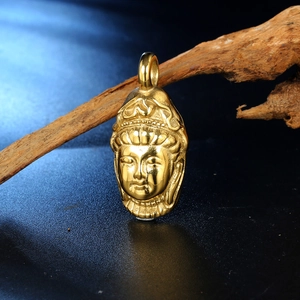 Primer plano de colgante cabeza de Buda en acero dorado pulido con fondo zen de madera