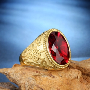 Close-up of vintage gold ring with a faceted red ruby stone and intricate carvings