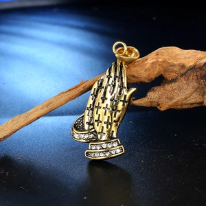 Detailed close-up of golden praying hands pendant with black crosses and white rhinestones