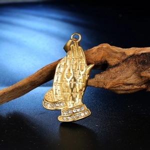 Detailed close-up of golden praying hands pendant with cross relief and rhinestones