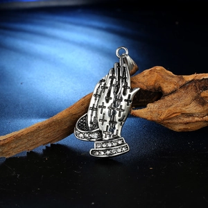 Close-up of vintage stainless steel praying hands pendant with cross and crystal details