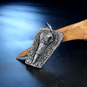 Détail macro d'un pendentif crâne de corbeau en acier titane vintage et ailes