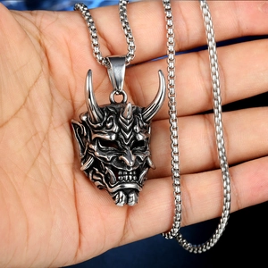 Detailed close-up of a silver gothic Hannya mask pendant held in hand for scale