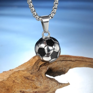 Détail d'un pendentif ballon de foot sur une chaîne argentée sur fond en bois rustique