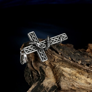 Vintage stainless steel cross pendant featuring a winding snake on a rustic wood background