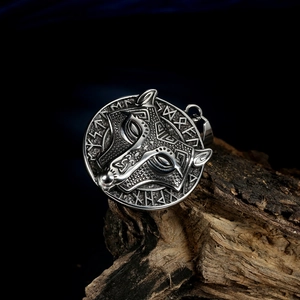 Detail of Viking wolf head pendant with runic alphabet on textured wood background