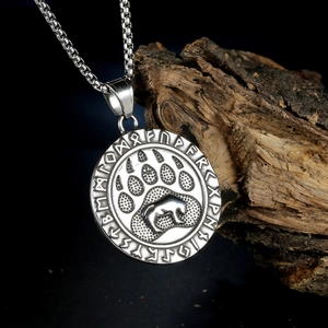 Vintage grizzly bear paw and runic pendant necklace on dark wood block background