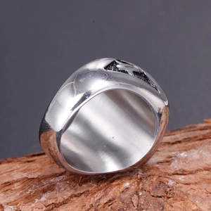 Detail of vintage stainless steel masonic ring on rustic wood background