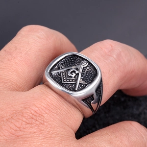 Macro side view of vintage stainless steel Freemason ring with G-symbol on male hand