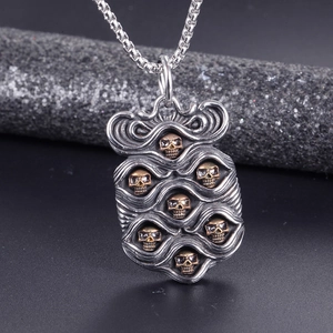 Macro detail of gothic punk skull pendant featuring seven gold skulls on textured titanium steel