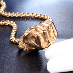Macro view of golden fist pendant necklace with detailed knuckles on box chain