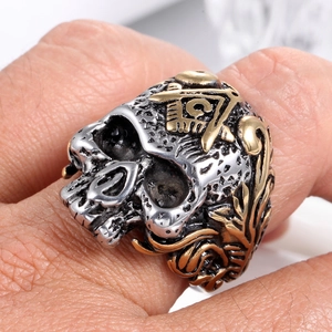 Detail view of silver and gold punk skull ring with Masonic compass symbol on man finger