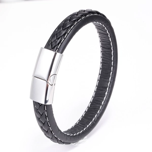 Détail d'un bracelet en cuir tressé noir avec surpiqûres blanches et fermoir magnétique en métal