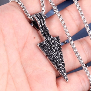 Détail macro d'un pendentif flèche en acier inoxydable de style punk avec texture