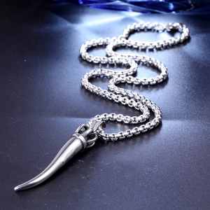 Macro detail of silver horn pendant on a round box chain with polished metallic finish