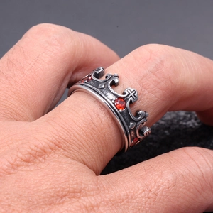 Nahaufnahme der Vintage Krone Ring mit roten Strasssteinen und Kreuz auf dunklem Steingrund