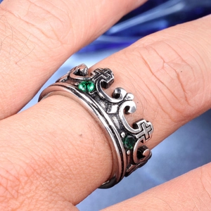 Detail eines Vintage Kronenrings mit grünen Steinen und Kreuzmuster am Finger