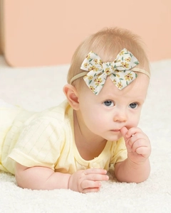 Close-up of a baby wearing a yellow floral bow headband made of soft elastic nylon