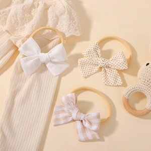 Three-piece set of baby nylon headbands with assorted bow designs on a soft lace background