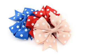 Detailed macro view of three polka dot grosgrain ribbon hair clips in blue, red, and pink