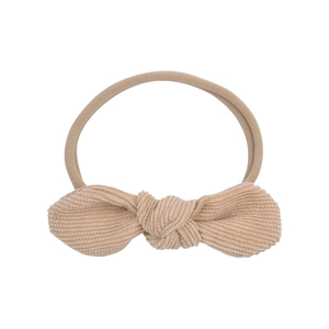 Detailed close-up of soft beige corduroy bow and elastic nylon headband for babies