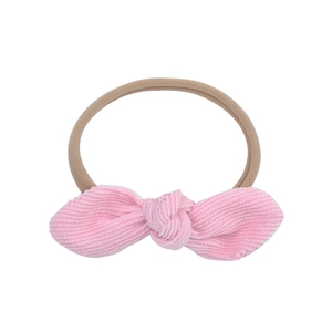 Detail of pink corduroy bow on skin-toned elastic nylon headband for babies