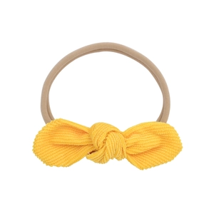 Detailed close-up of yellow corduroy bow baby headband with soft nylon elastic strap