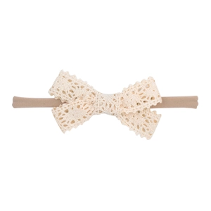 Close-up of soft cream white lace bow baby headband with stretchy nylon elastic band