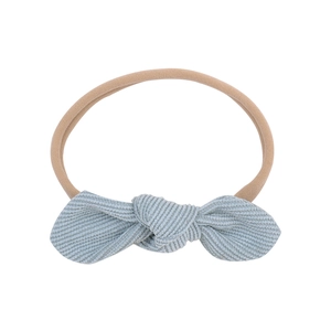 Detail of light blue corduroy bow on a soft nude nylon headband for babies