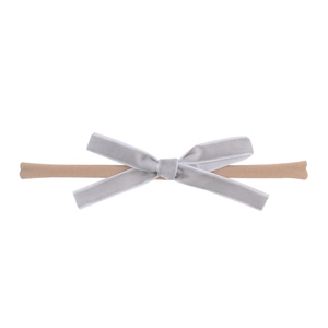 Detail of baby headband featuring grey velvet bow and nude nylon elastic band