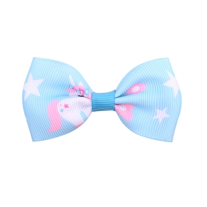 Dettaglio del fiocco per capelli da bambina con motivi azzurri di unicorni e stelle