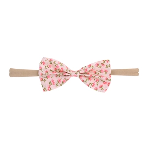 Close-up of baby headband featuring a floral fabric bow and soft nylon elastic band