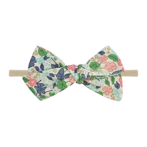 Détail d'un bandeau pour bébé avec nœud à motifs floraux et élastique en nylon doux