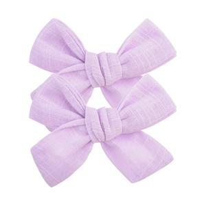 Détail de deux barrettes nœuds en coton lilas montrant la texture douce du tissu