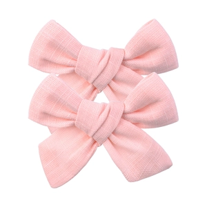 Détail de nœuds en tissu rose montrant la texture naturelle du lin et le nœud fait à la main