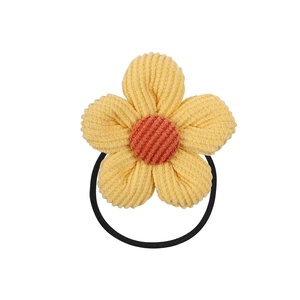 Detailed close-up of a yellow corduroy flower hair tie with orange center and black elastic band