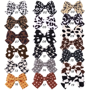 Detailed grid of 18 bow hair clips in leopard print, polka dots, and checkered fabric