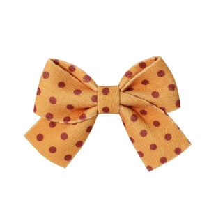 Detail of fabric bow hair clip featuring retro orange and brown polka dot patterns