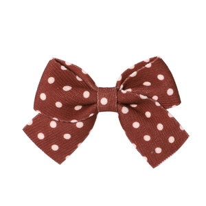 Detailed view of the brown polka dot bow hair clip with vintage textile fabric texture