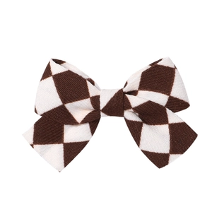 Close-up of brown and white checkered fabric bow hair clip with vintage texture