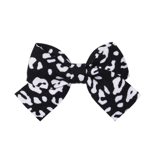 Detailed close-up showing the fabric texture of black and white milk pattern bow hair clip