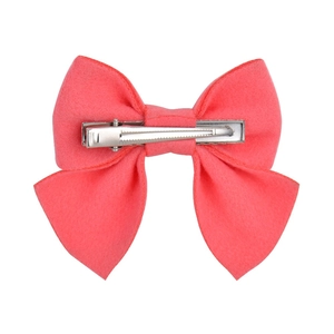 Détail de la pince crocodile en métal argenté sur un nœud papillon en tissu rose corail