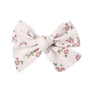 Close-up detail of floral cotton bow hair clip with pink flowers and green leaves