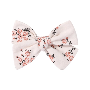 Detail shot of a floral cotton bow hair clip with orange flowers and linen texture