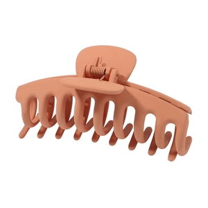 Detail of a large matte orange-red hair claw clip with a strong metal spring structure